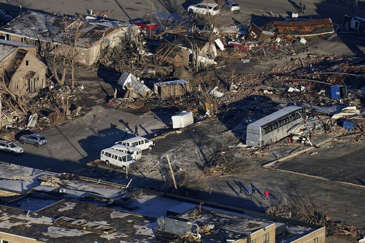 In a view from this aerial photo, people walk amidst destruction from a recent tornado in downtown Mayfield, Ky., Sunday, Dec. 12, 2021. (AP Photo/Gerald Herbert)