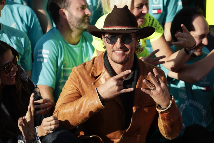Matthew McConaughey makes hand gestures while wearing a cowboy hat in a crowd