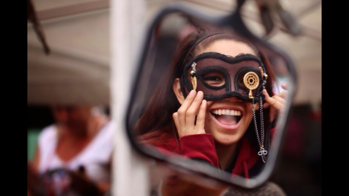 Felicia Rio, 19, of Modesto, tries on a mask at one of the merchandise booths at the 45th annual San Francisco Pride Celebration & Parade held on Sunday.