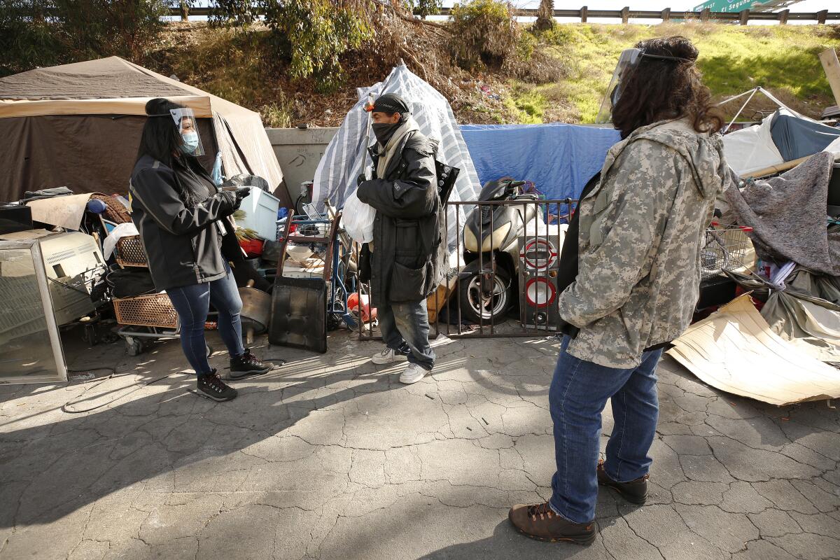 Three people at a homeless camp.