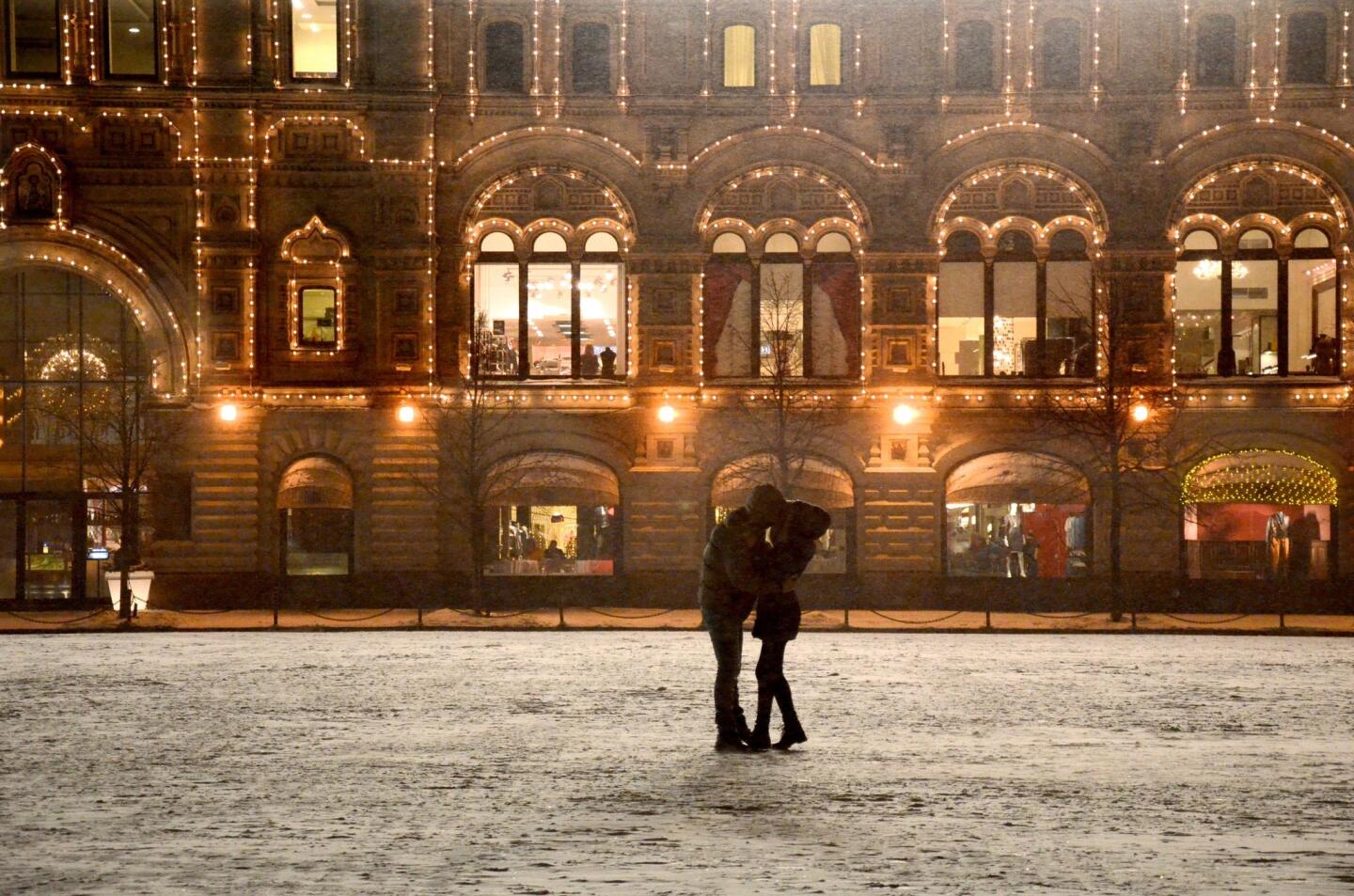 A couple embraces outside GUM, an arcade-style, three-level shopping center on Red Square that is housed in an 1890s structure.