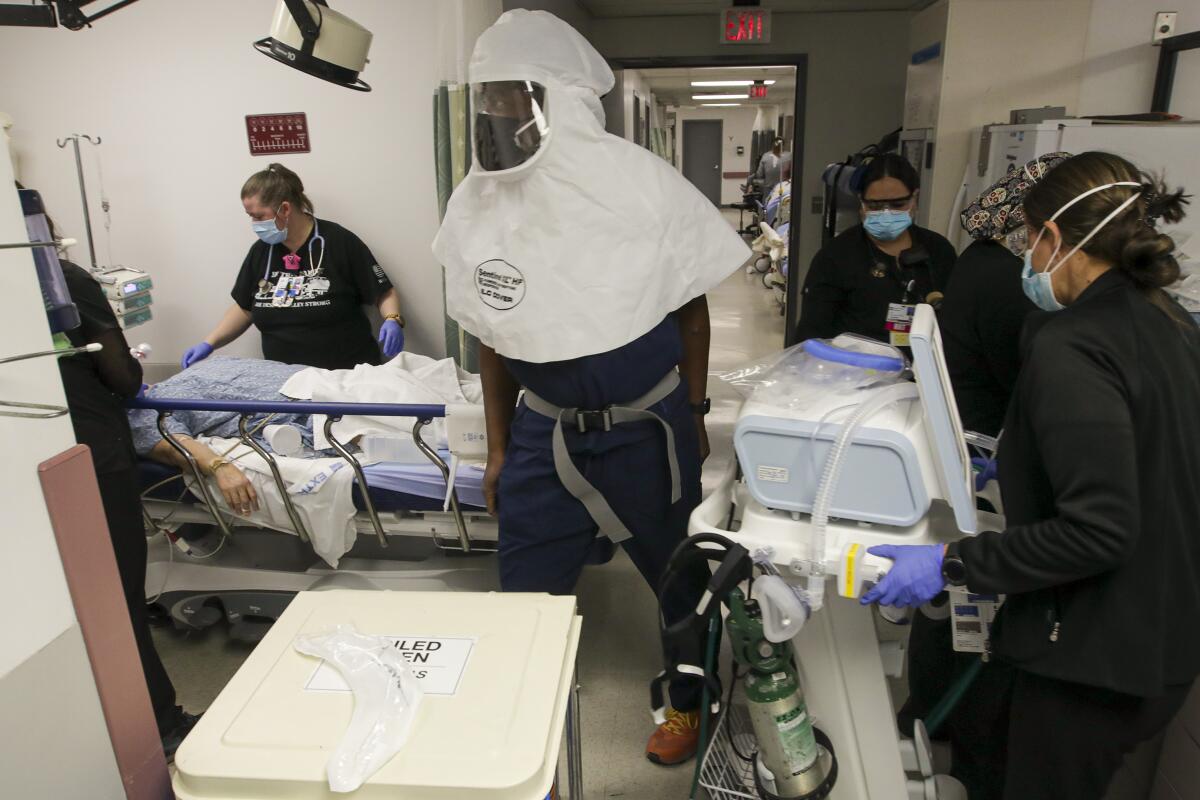 Masked healthcare providers attend to a hospital patient