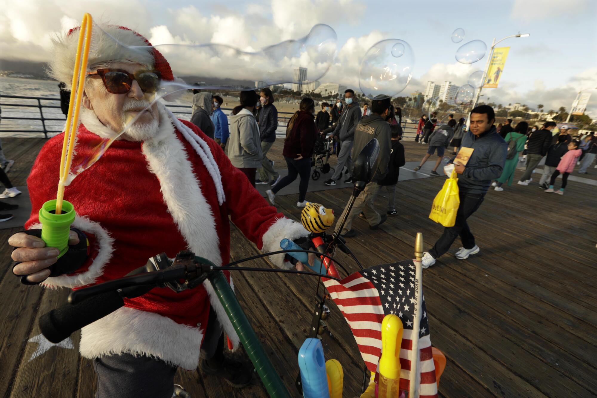 Sid Lindenbaum blows bubbles while dressed as Santa on Christmas Eve at  the Santa Monica Pier. 