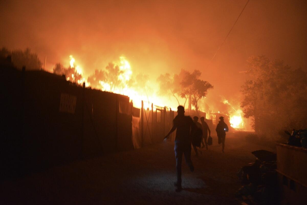 People run away as a fire burns Wednesday in the Moria refugee camp on the Greek island of Lesbos.