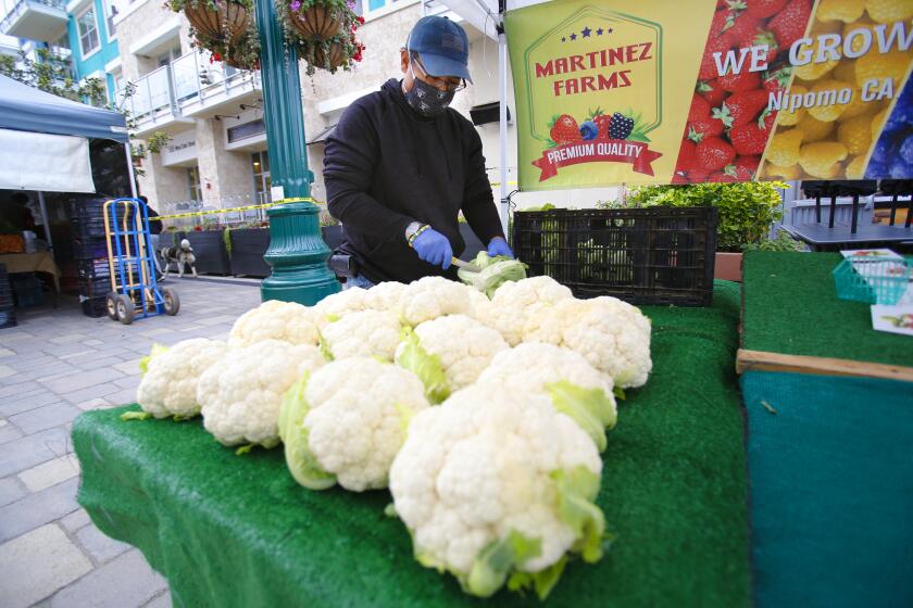 Ted Piano front the Martinez Farm prepared cauliflower for customers at the Farmer Market in Little Italy on Saturday.