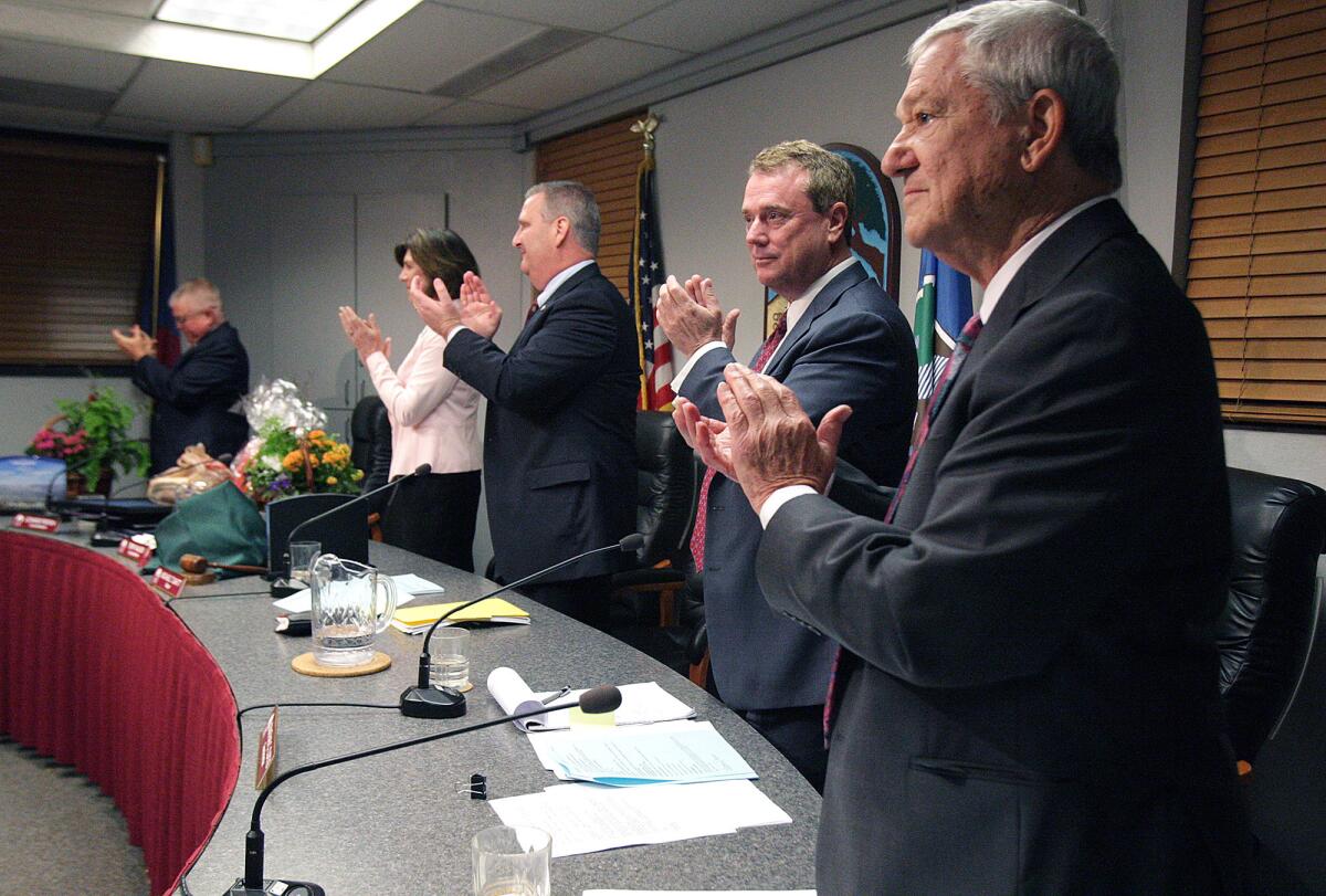 Under the direction of newly appointed Mayor Dave Spence, right, outgoing council members Laura Olhasso and Donald Voss are given a standing ovation at La Cañada City Hall on Monday, March 16, 2015.