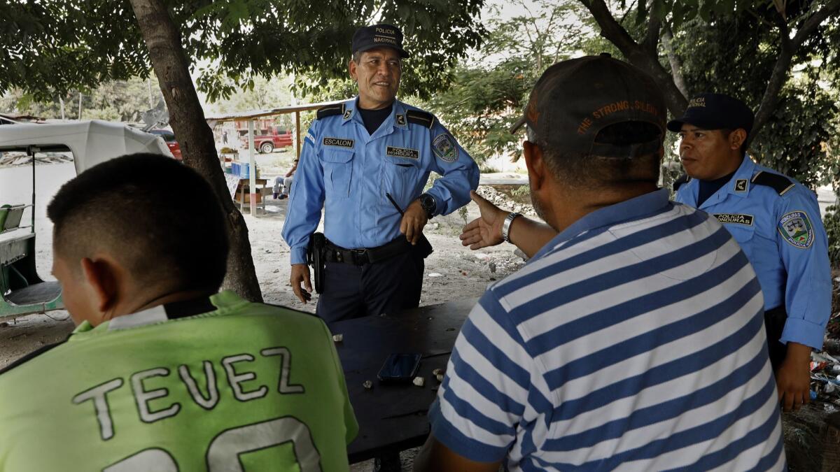 BORDO DEL RIO BLANCO, HONDURAS--NOV.7, 2018--Police officer Domingo EscalÃ³n, age 50, (center) was trained in community policing around the world including via programs provided by the U.S. embassy and knows members of the community by name. He knows everyone in the neighborhood of Bordo del Rio Blanco, where crime has been reduced in recent years. (Carolyn Cole/Los Angeles Times)