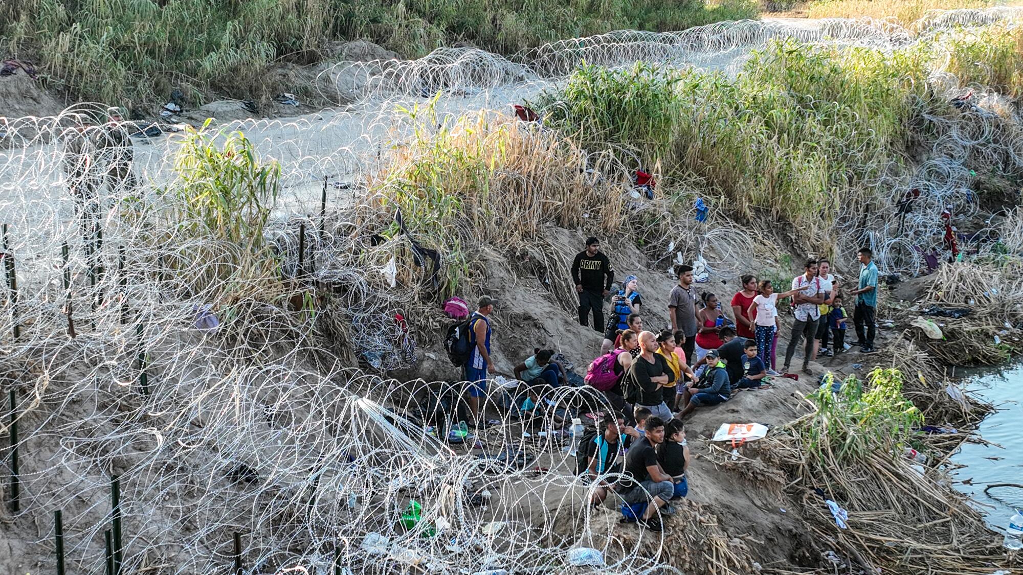 Migrants gather behind razor wire after crossing the Rio Grande into Eagle Pass, Texas.