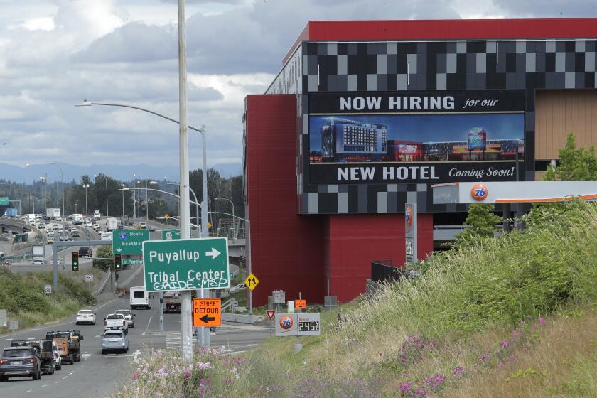 FILE - In this July 9, 2020, file photo, a large video display reads "Now hiring for our new hotel coming soon!," at the new Emerald Queen Casino, which is open, and owned by the Puyallup Tribe of Indians, in Tacoma, Wash. The United States added 1.8 million jobs in July, a pullback from the gains of May and June and evidence that the resurgent coronavirus has weakened hiring and the economic rebound. (AP Photo/Ted S. Warren, File)