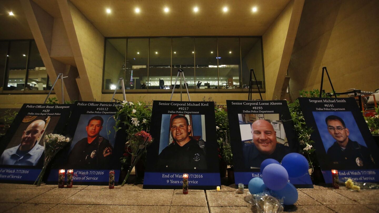 Five portraits of the officers killed last week are displayed at the vigil.
