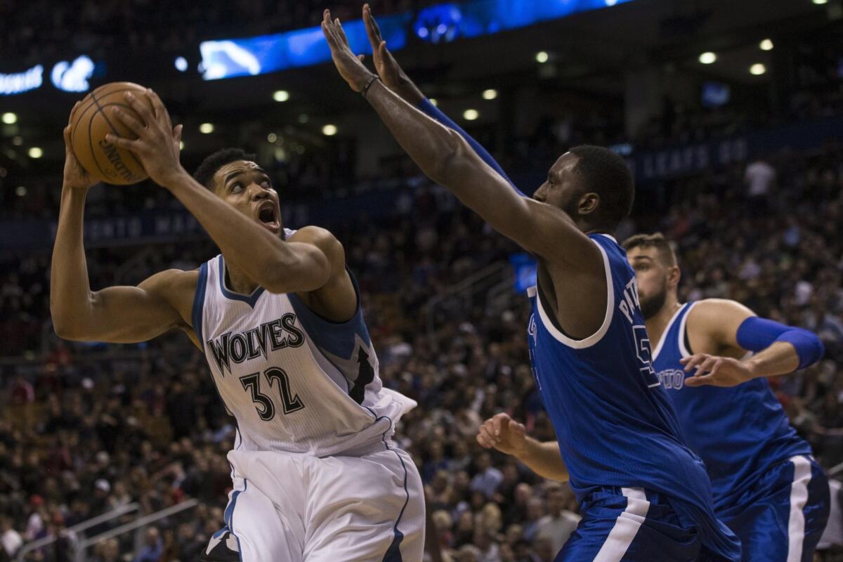 Minnesota Timberwolves centre Karl-Anthony Towns, left, turns to shoot on Toronto Raptors forward Patrick Patterson during the second half of an NBA basketball game in Toronto on Thursday, Dec. 8, 2016.