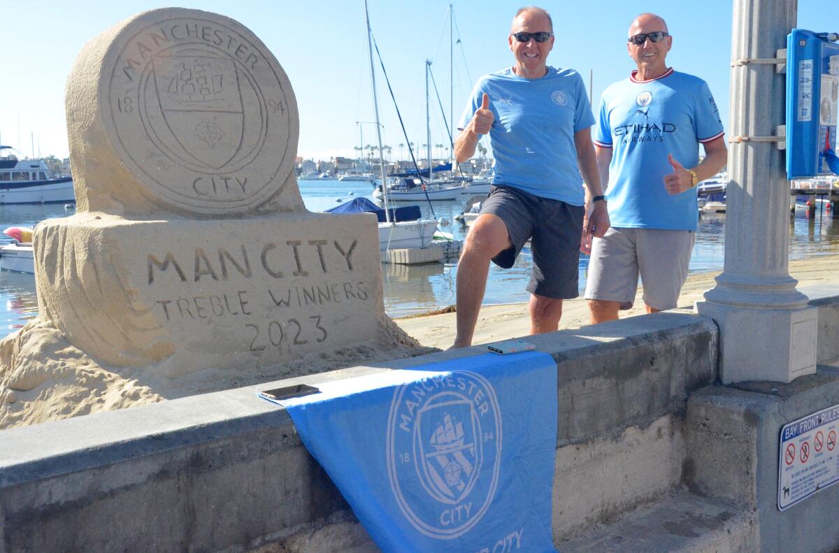 Colin Broadbent and Dennis Layton pose with the Man City sand sculpture by Chris Crosson.