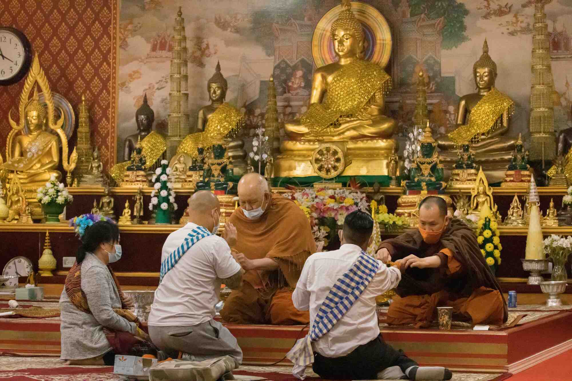 Lina Vongsy, and her sons Salalai and Donnie are given string wrist bands by Buddhist monks 