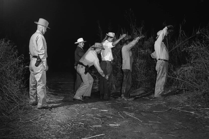 Border Patrol officer searches four illegal immigrants caught entering California from Mexico. This photo appeared in the May 2, 1950, Los Angeles Times.