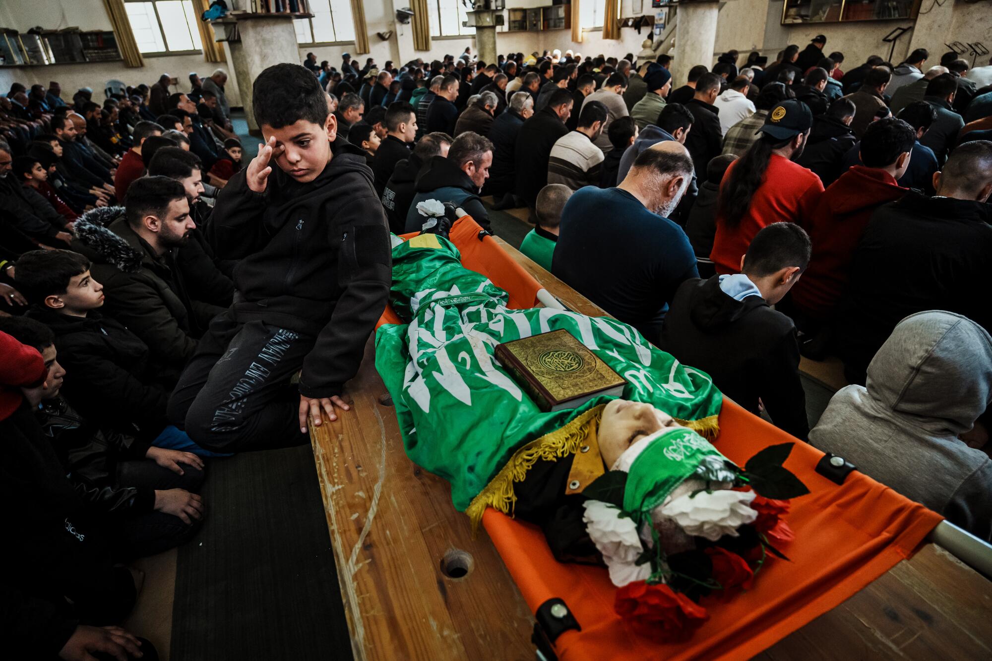 ナシーム・マジディ君（12歳、中央）は友人のアムロ・ナジャールさんの遺体の隣に座っている。