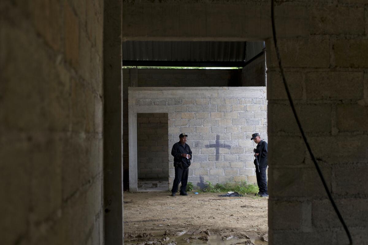 State police stand inside a warehouse where a black cross covers a wall near blood stains on the ground in Tlatlaya, Mexico. The army initially said 22 people were killed on June 30 in a gun battle between soldiers and an armed gang. But journalists found evidence that suggested a one-by-one killing of gang members.