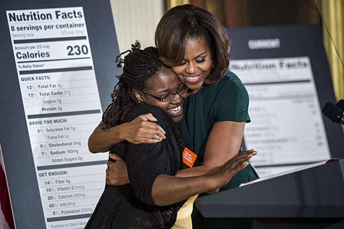 Shanese Bryant-Melton hugs First Lady Michelle Obama during an event about new nutrition labels held in the East Room of the White House.