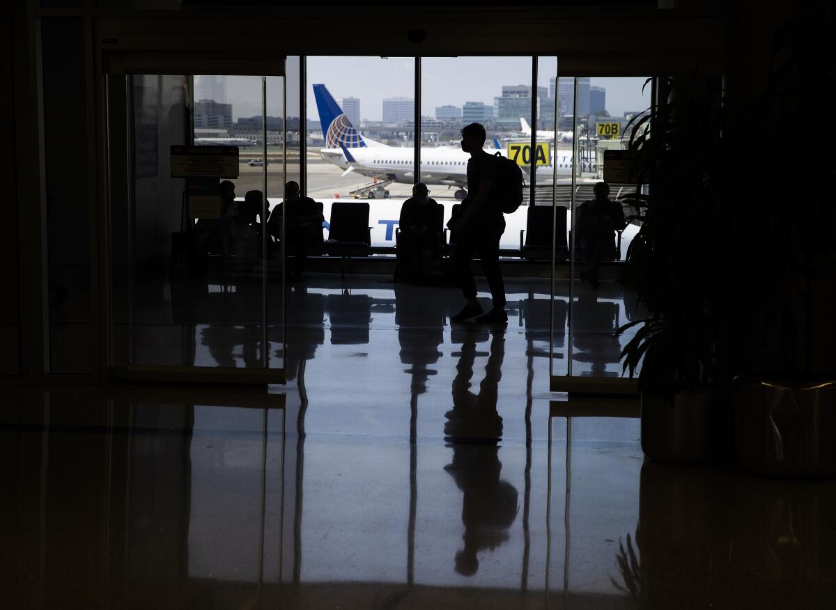 Travelers at LAX wait in a gate area.