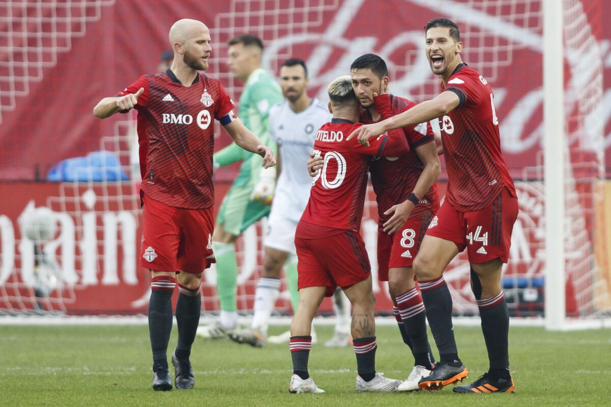 Toronto FC midfielder Marco Delgado (8) celebrates his goal with teammates Yeferson Soteldo (30), Michael Bradley (4) and Omar Gonzalez (44) during first half MLS soccer action against the Chicago Fire, in Toronto, Sunday, Oct. 3, 2021. (Cole Burston/The Canadian Press via AP)