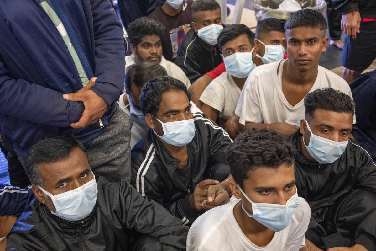 Migrants wait aboard a ship