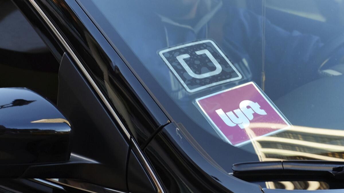 A driver displaying Lyft and Uber stickers on his front windshield drops off a customer in downtown Los Angeles.