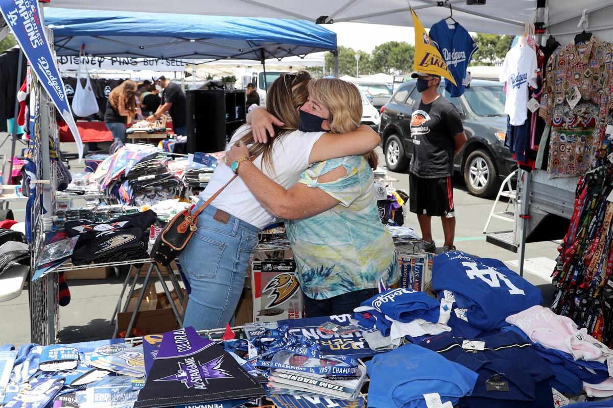 Kim Garibay, right, The Packham Company owner, hugs customer Jenna Novela O.C. Swap Meet at the fairgrounds in Costa Mesa