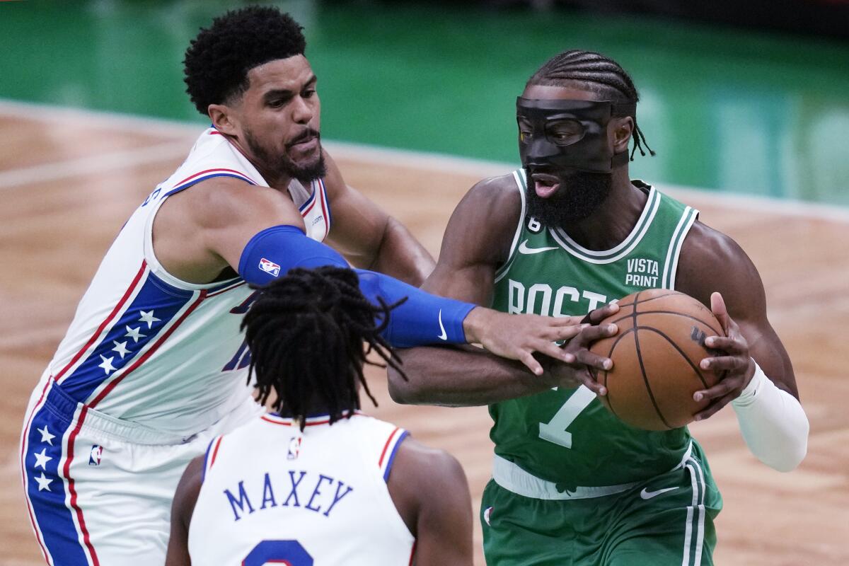 Jaylen Brown, de los Celtics de Boston, avanza hacia la cesta frente a Tobias Harris y Tyrese Maxey, 