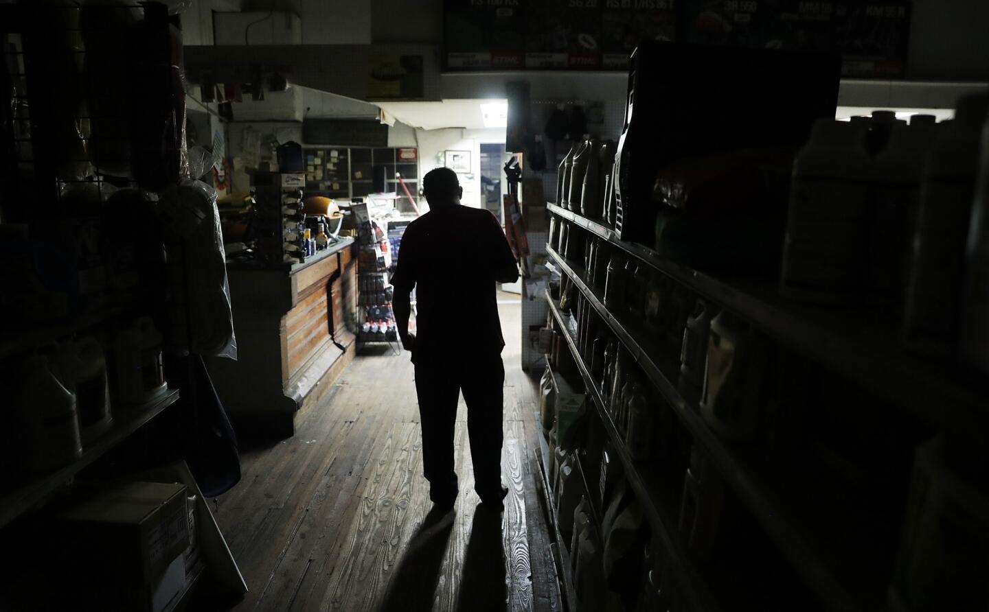 Trey Tait watches over his store, Tait's Lawn Products, illuminated by a generator after the power went out from Hurricane Matthew in Brunswick, Ga., on Oct. 7, 2016.