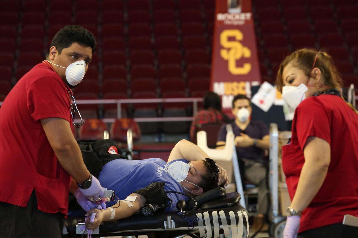 Red Cross technician Eddie Valdivia, left, and nurse Mercy Pineda work with a donor as USC Athletics and the Red Cross host a blood drive.