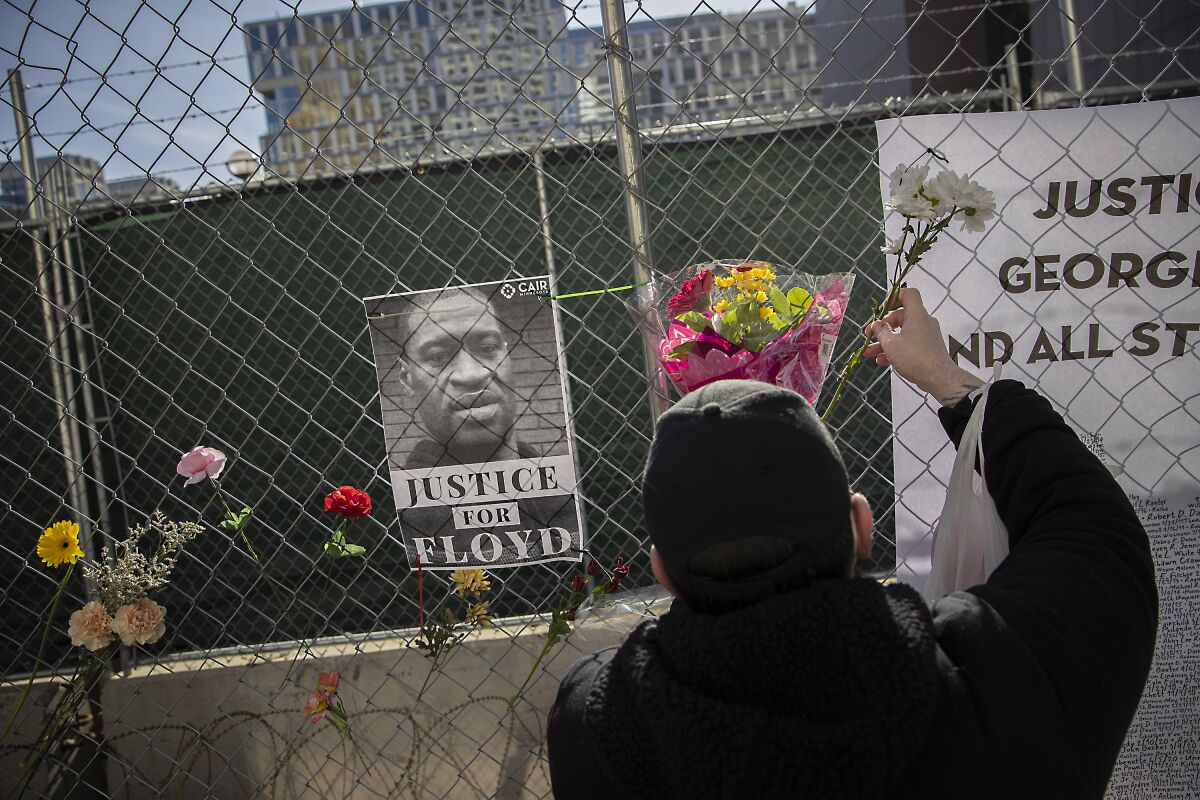 A man places flowers outside the Minneapolis courthouse where Derek Chauvin is on trial for the death of George Floyd.