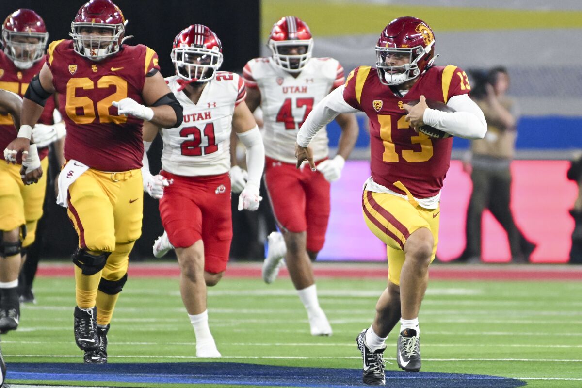 USC quarterback Caleb Williams runs with the ball while pulling away from the Utah defense.