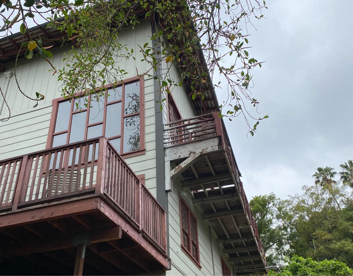 Ground-level view looking up at balconies on a green-painted wood home