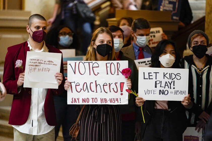 Protesters carry signs at a rally held in opposition to bills being considered at the Statehouse in Indianapolis, Wednesday, Feb. 16, 2022. Bills, HB 1041 that would ban trans girls from school sports and HB 1134 that would limit how students can learn and talk about race and sex discrimination in public schools, are both in front of the Senate Education Committee. (AP Photo/Michael Conroy)
