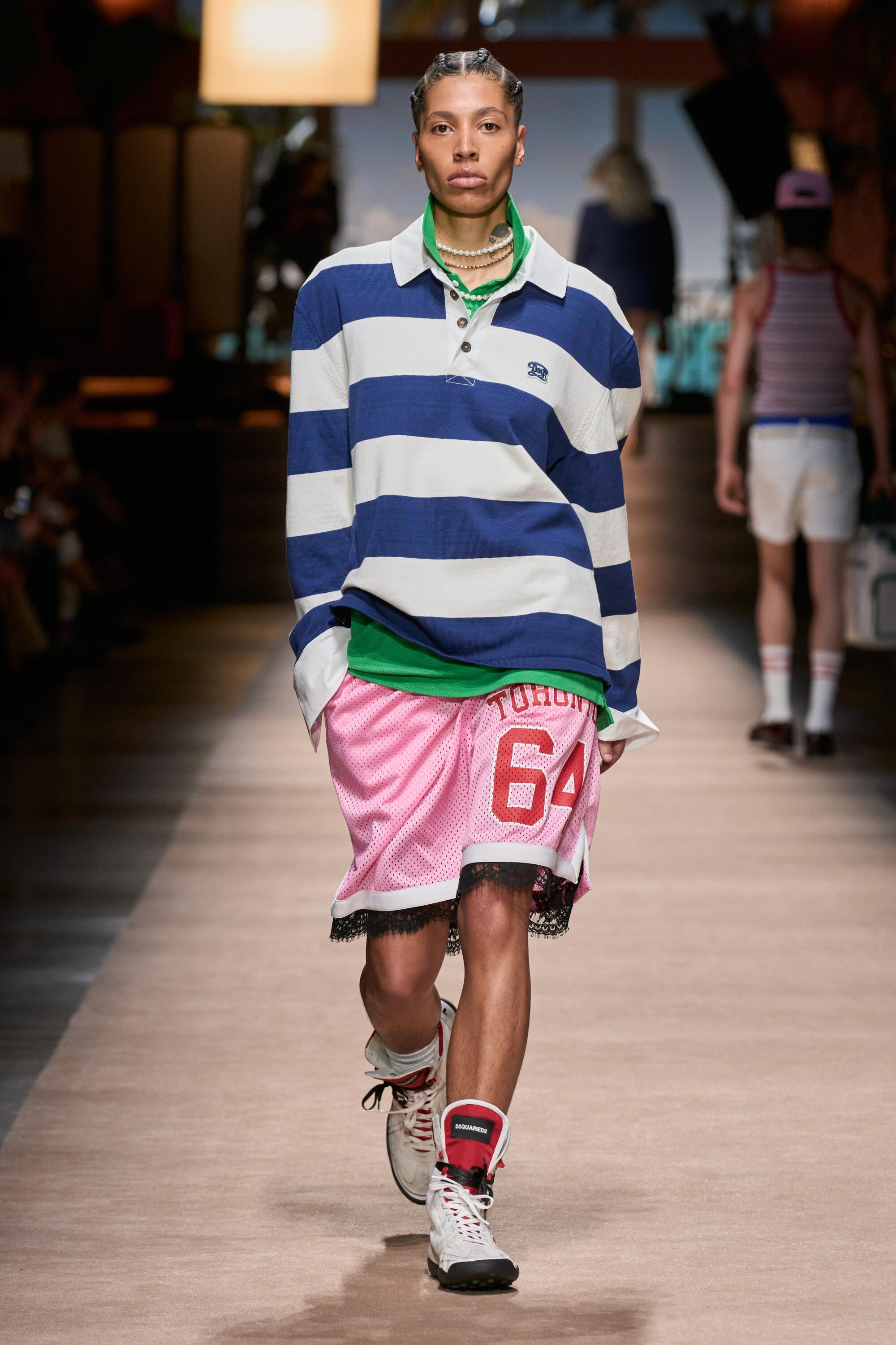 A model wearing a blue and white striped shirt and pink shorts with a red 64 on one leg.