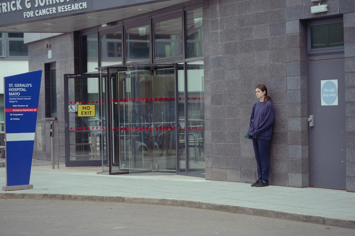 A young woman stands outside a hospital