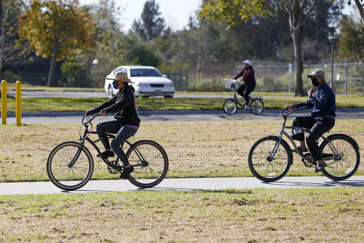 Cyclists wearing masks ride through Mile Square Regional Park in Fountain Valley on Tuesday.