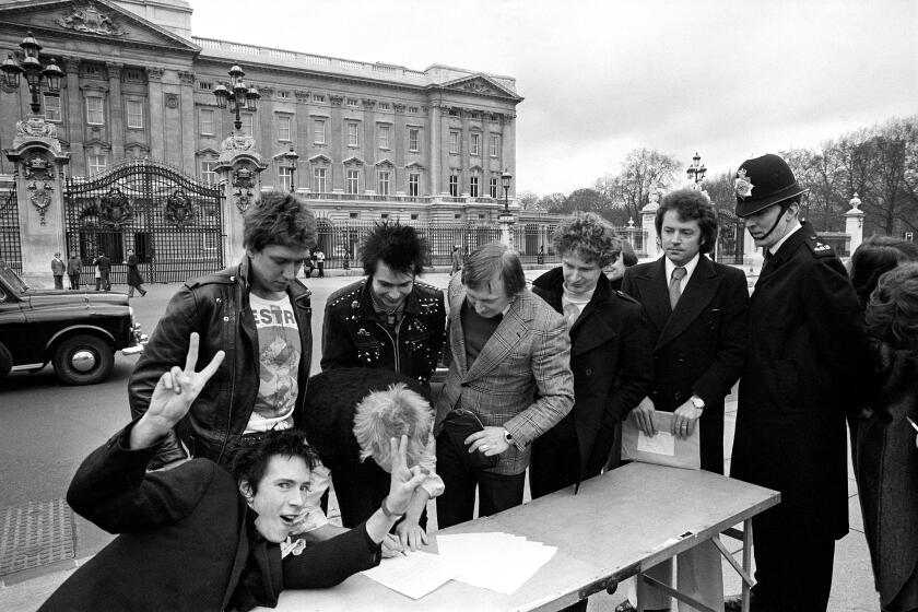 The Sex Pistols sign a copy of their new recording contract with A & M Records outside Buckingham Palace in 1977.