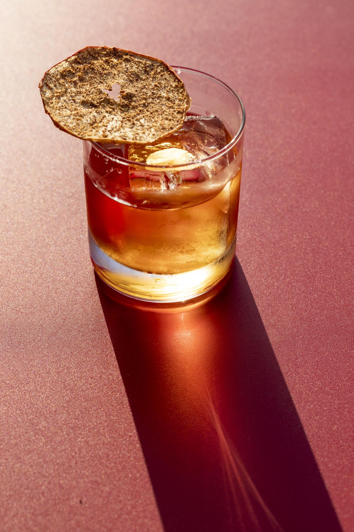 A bagel chip sits atop a drink.