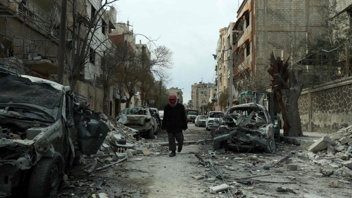 A Syrian man walks next to damaged buildings Sunday after airstrikes in the Syrian rebel-held town of Duma.