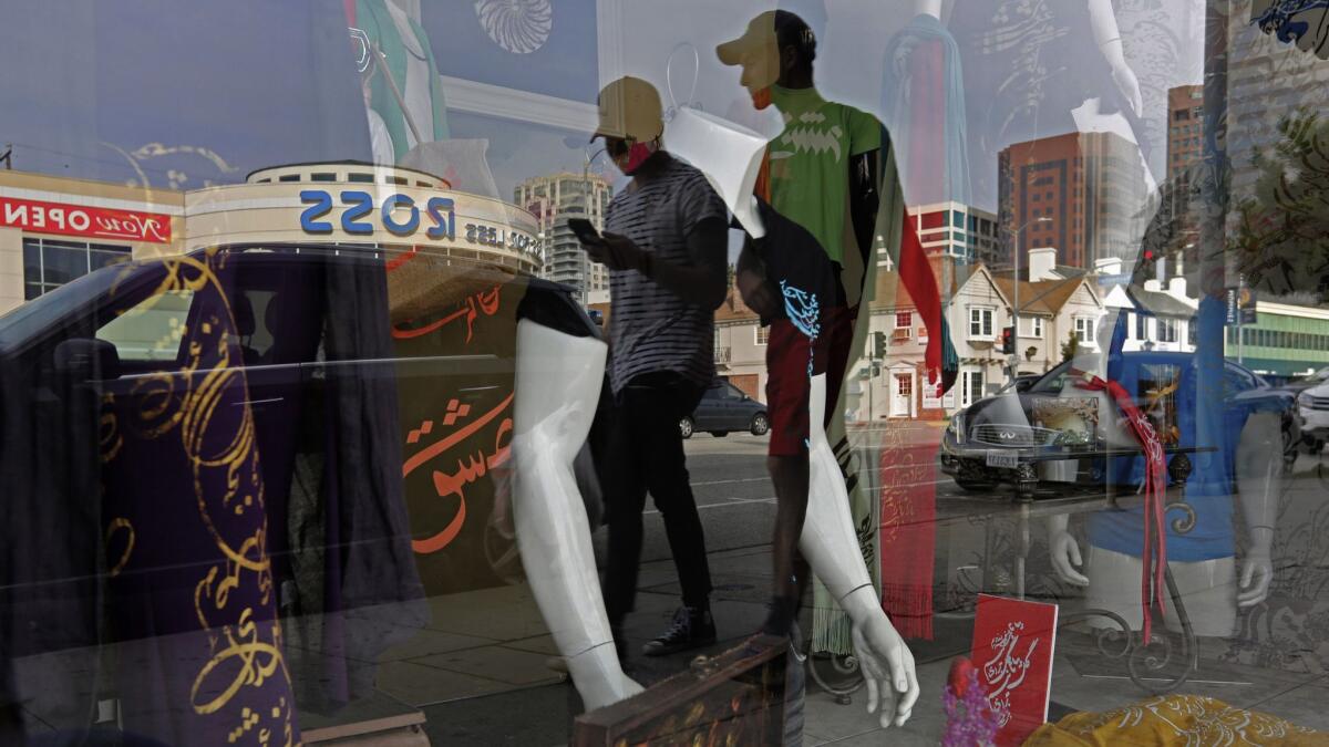 People are reflected in a storefront as they walk down Westwood Boulevard in Los Angeles' Persian Square district.