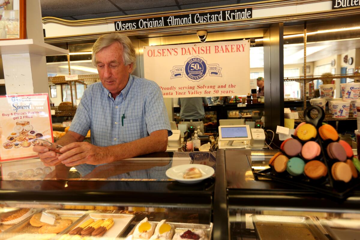 A man leans on a glass counterspace filled with pastries