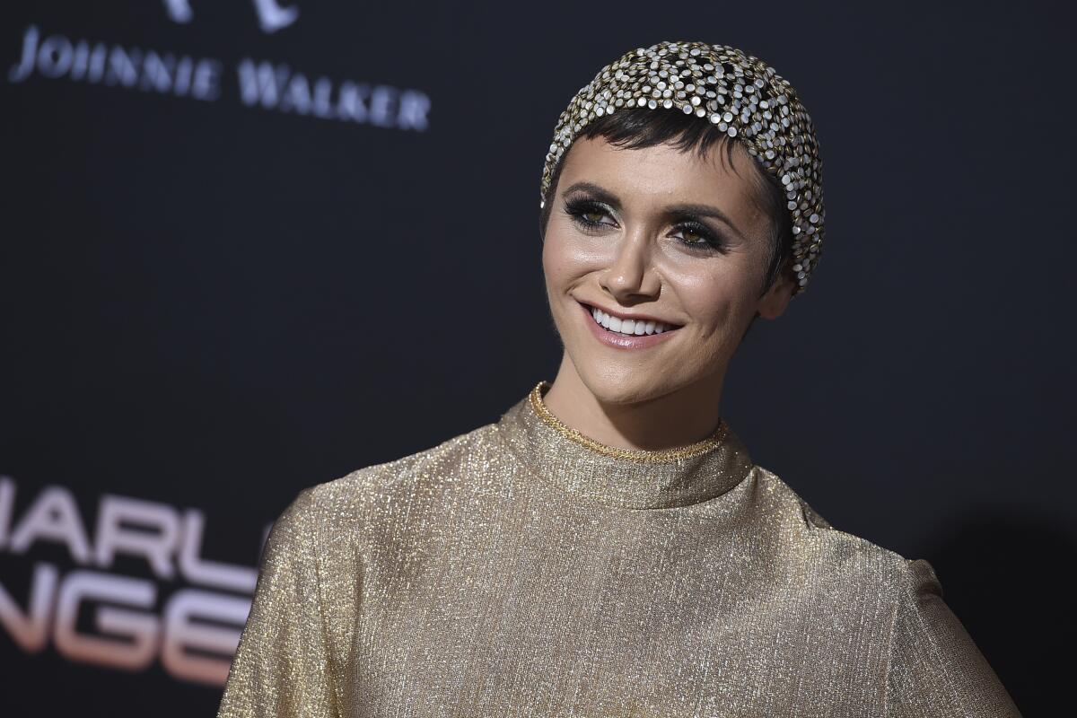 Alyson Stoner poses for photos in gold long-sleeve shirt and sequined beanie.