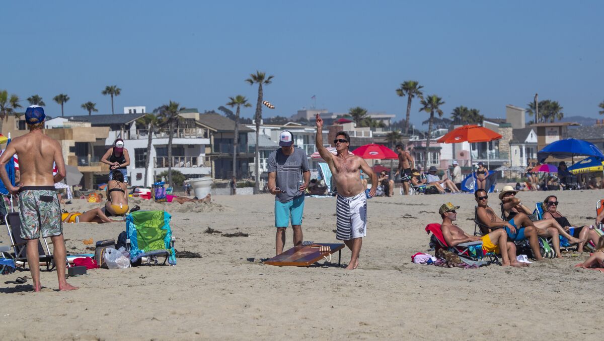 People play beanbag toss on the sand in Newport Beach on Saturday.