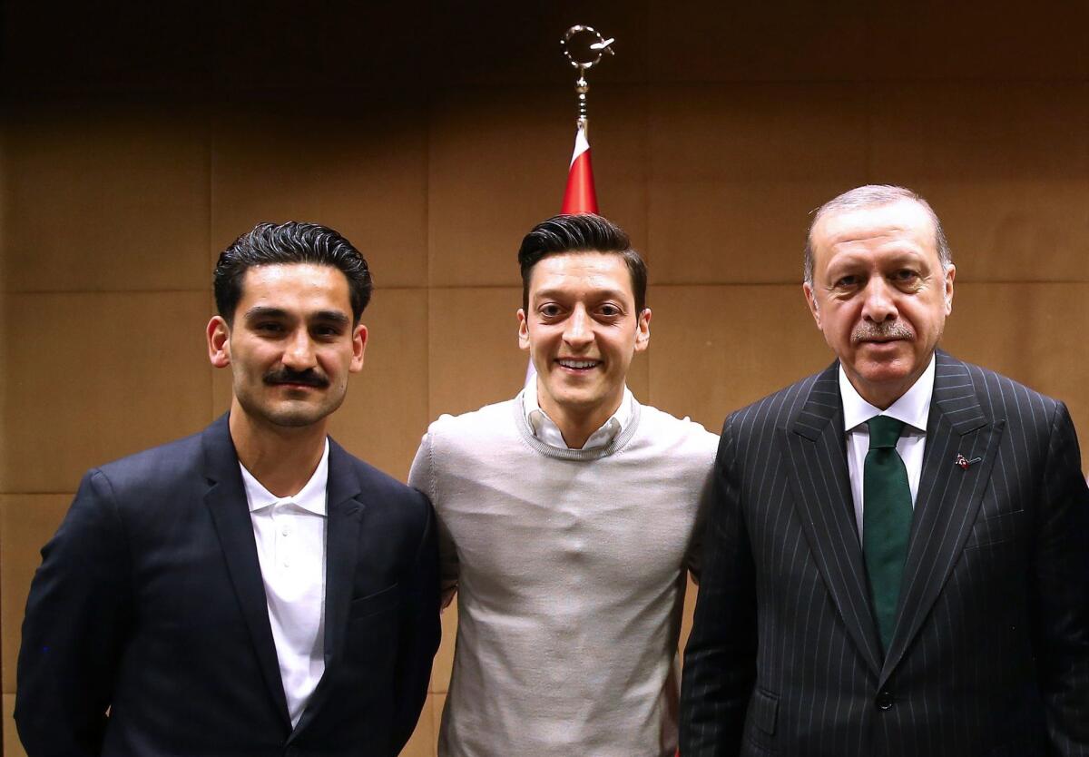 In this handout picture taken on May 13, 2018 and released on May 14, 2018 by the Turkish Presidential Press office Turkish President Recep Tayyip Erdogan (R) poses for a photo with German footballers of Turkish origin Ilkay Gundogan (L) and Mesut Ozil (2nd L) in London. Since Germany humiliatingly crashed out of the World Cup, Mesut Ozil, 29, quickly become a scapegoat for far-right populists, but the storm escalated when even German football bosses, rather than defend him, suggested the squad may have been better off without him.
