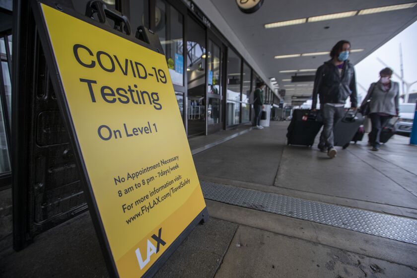 LOS ANGELES, CA - NOVEMBER 23: Travelers pass by a sign advertising the COVID-19 testing station at LAX Terminal 2 Lower/Arrivals Level as the Thanksgiving holiday getaway period gets underway on Monday, Nov. 23, 2020 in Los Angeles, CA. Millions of Americans are carrying on with their travel plans ahead of Thanksgiving weekend despite the CDC's urgent warnings to stay home as the number of daily cases and hospitalizations in the country continue to hit record highs. Confirmed cases in the U.S. for the disease topped 12 million on Saturday as more than 193,000 new infections were recorded in the US on Friday. This broke the previous record for the largest single-day spike on Thursday - and over 82,000 patients are now hospitalized across the country. (Allen J. Schaben / Los Angeles Times)