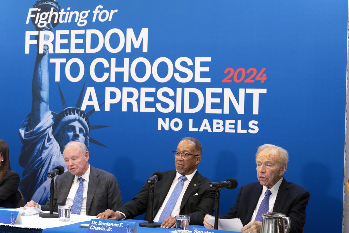 Three men sit at a table in front of a blue background reading:  Fighting for Freedom to Choose a President 2024 No Labels
