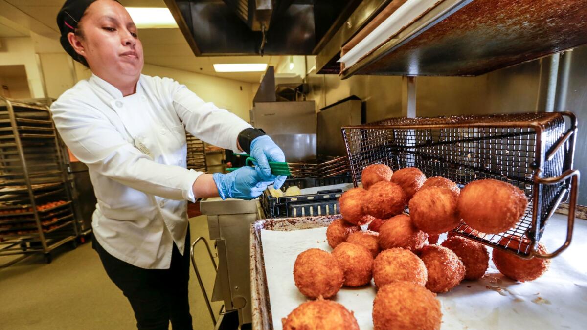 Mara Serrano fries potato balls at Porto's in Glendale. (Irfan Khan / Los Angeles Times)