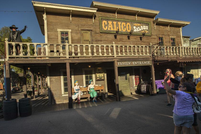 BUENA PARK, CA -JULY 31, 2020: Clay Mayfield, above left, dressed up as an outlaw, waves to visitors during Knott's Tase of Calico event at Knott's Ghost Town in Buena Park. Knott's Taste of Calico is a specially ticketed, limited-time outdoor dining and retail experience. (Mel Melcon / Los Angeles Times)