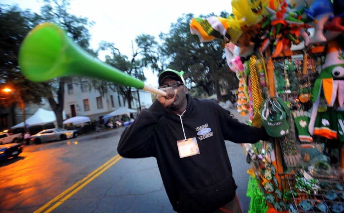 Georgia street vendor Marshall Baker blows a horn to attract customers before the start of Savannah's 190-year-old St. Patrick's Day parade Monday.