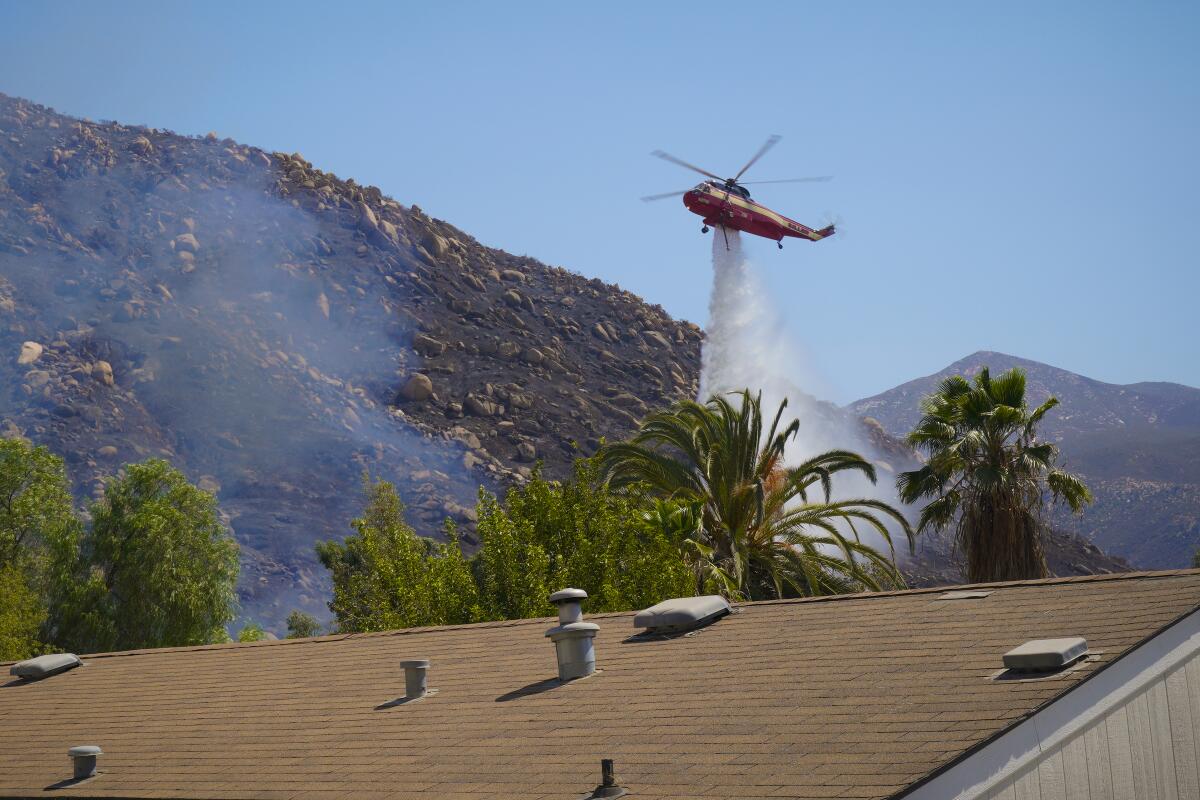 A helicopter drops water onto a brush fire that threatened homes near Barrett Lake Mobile Home Park on Thursday, Sept. 1.